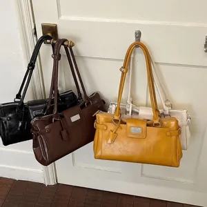 Black, brown and tan shoulder bags hanging from hooks on a white door