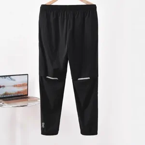 Black joggers with reflective strips above the knees, hanging against a white wall